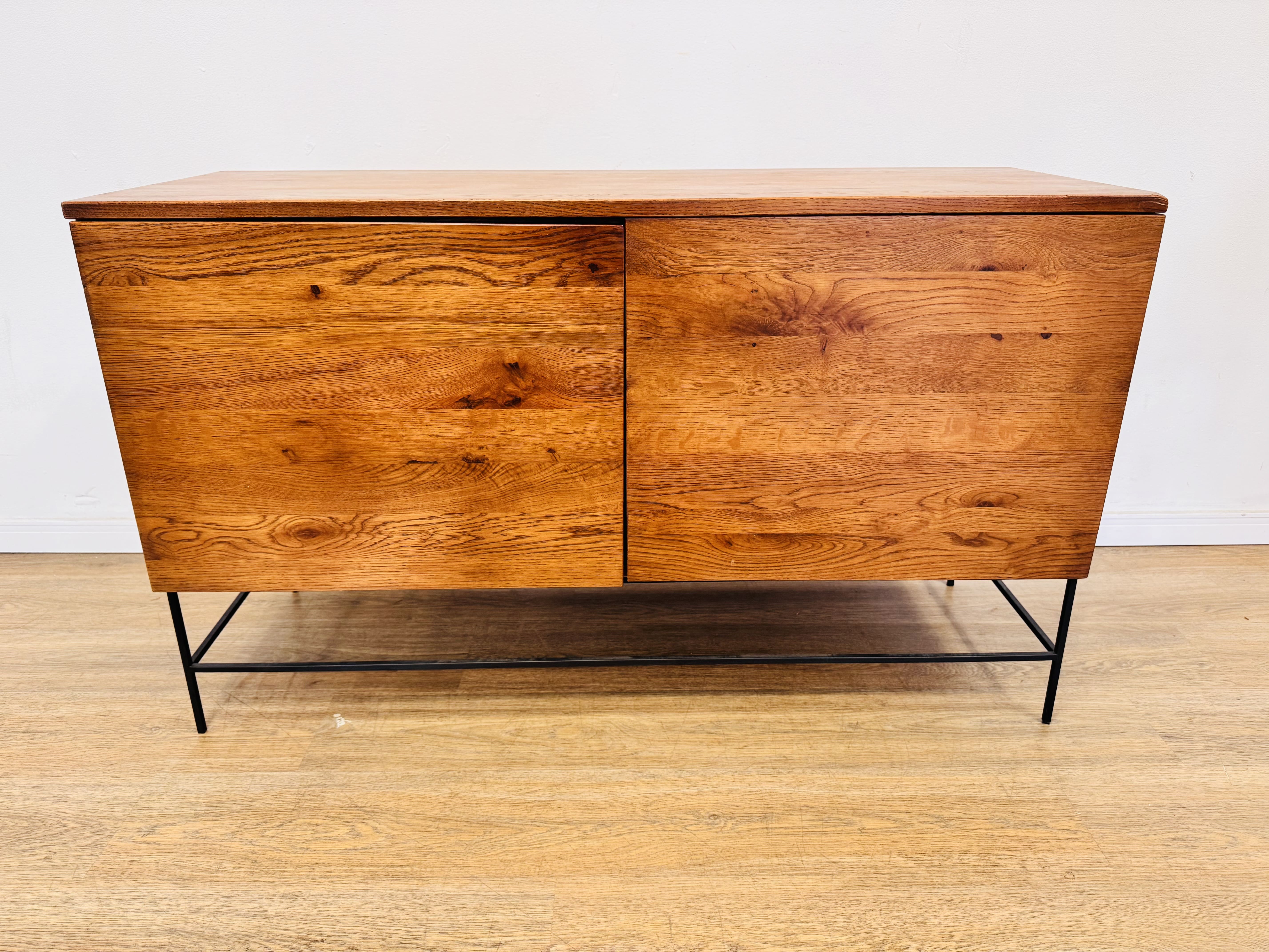 Lote #154 - Aparador/ Rack en madera maciza con patas de hierro, dos puertas - 125x45x75cm - SIN USO, de importante mueblería