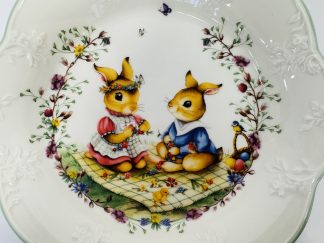 Lote #011 - Plato hondo de porcelana de la marca Villeroy & Boch, motivo infantil con conejitos y flores, borde ondulado con relieves florales (25cm) más huevero decorativo con motivo de conejo de la colección limitada  Bunny Tales. Sin uso, 8x6cm
